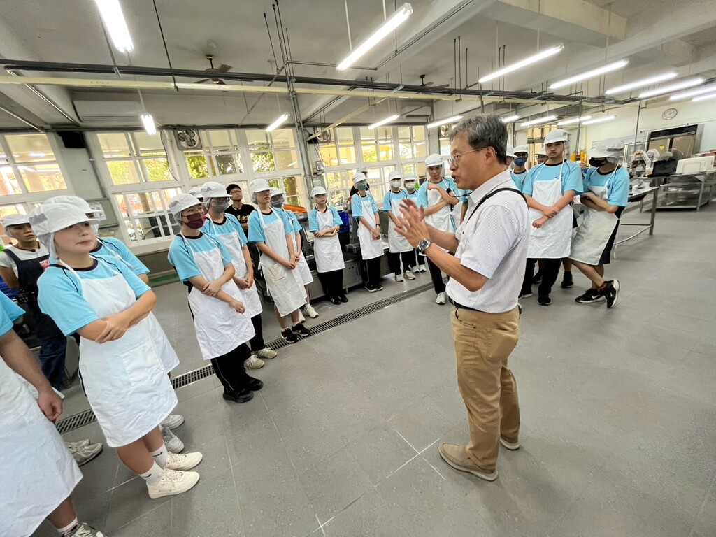 元培食科系梁弘人主任於實作場域說明莫扎瑞拉起司的做法，引導關西高中學生分組操作。圖片